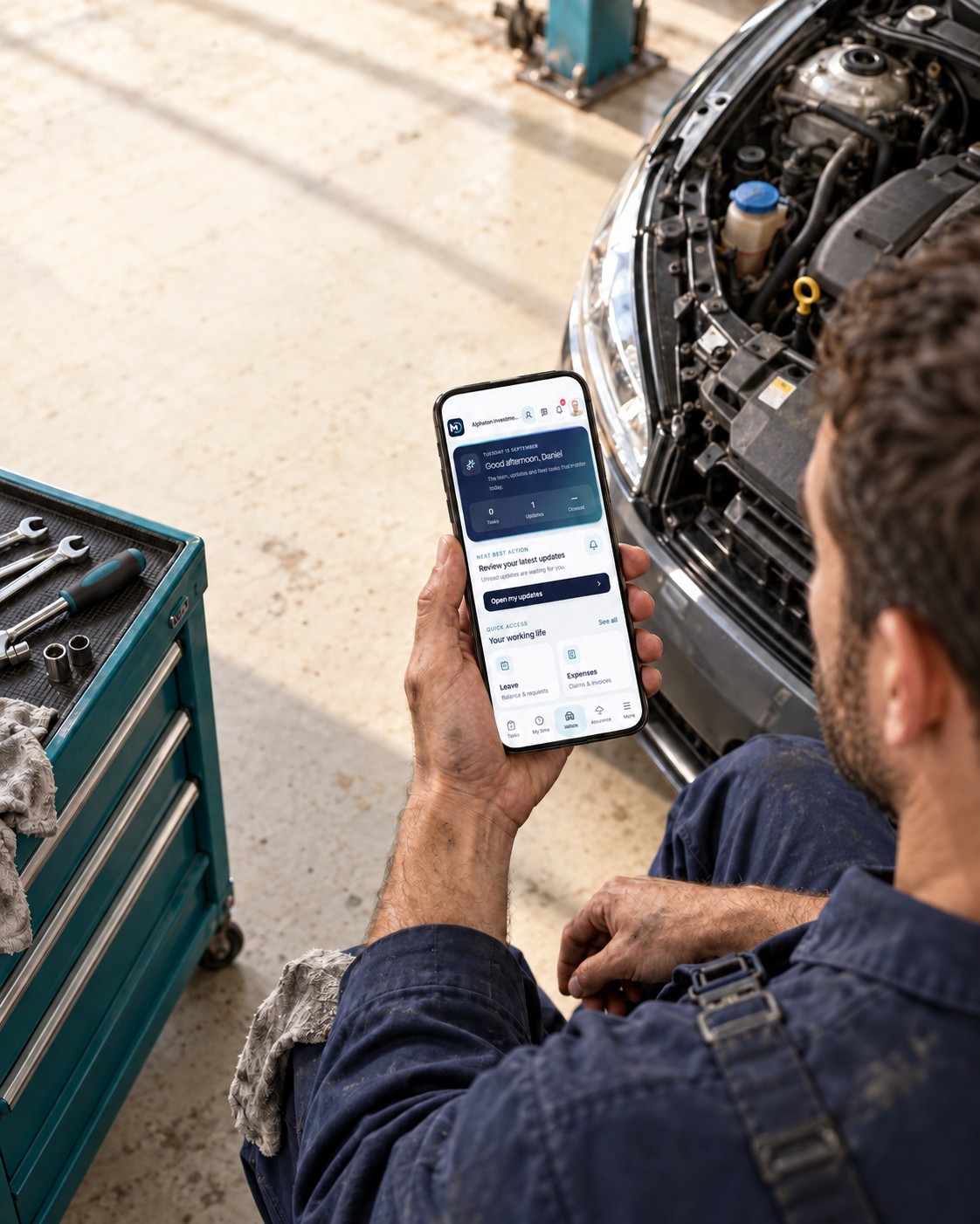 A mechanic checking the MyDekela app beside a car in a workshop.